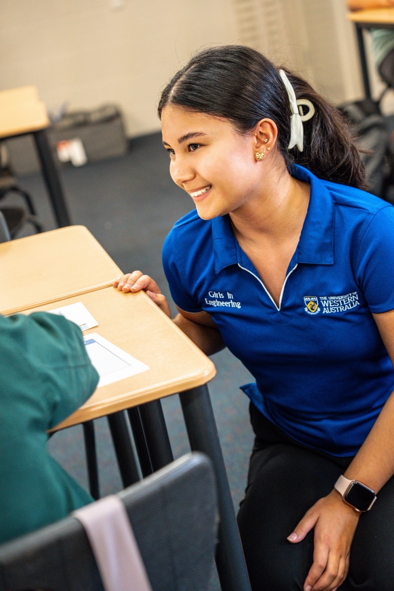 Taleena mentoring a student while wearing a UWA Girls in Engineering polo